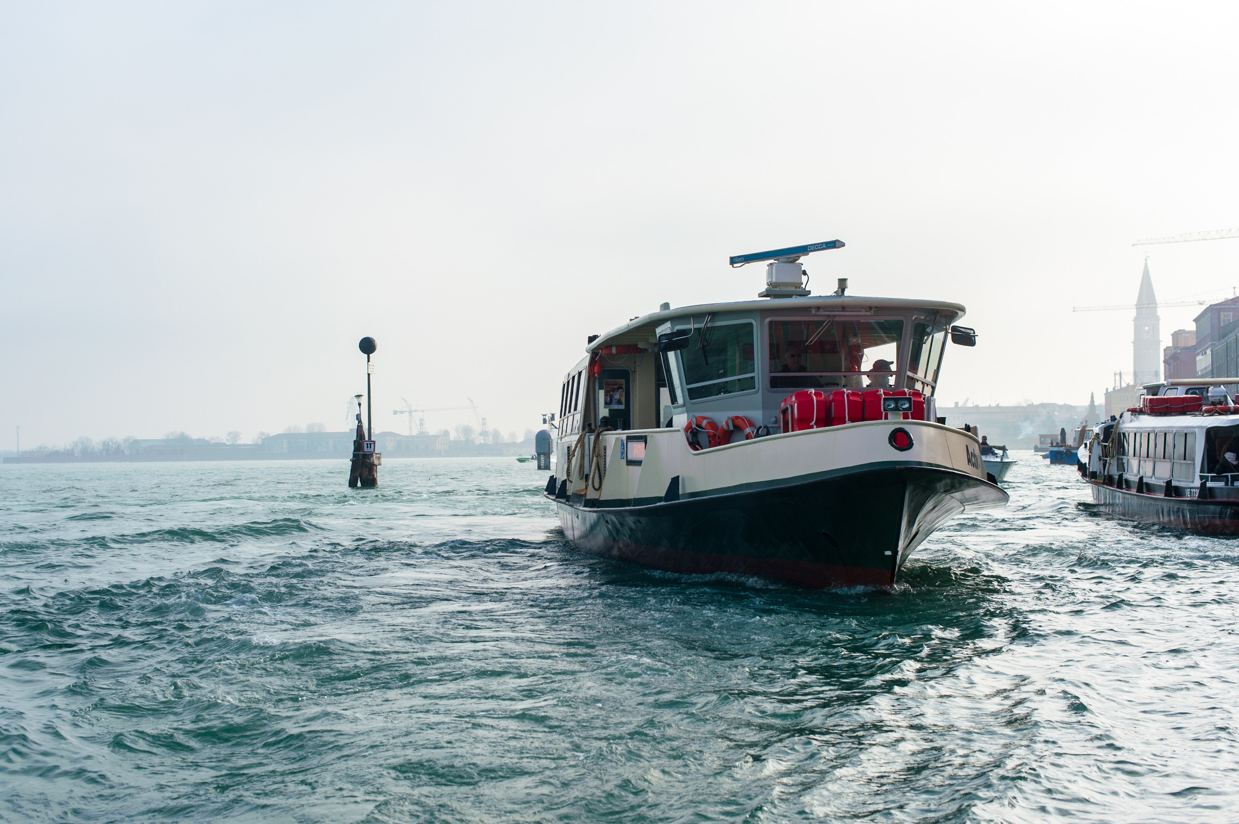 Passenger boat sailing through canal with cityscape in background