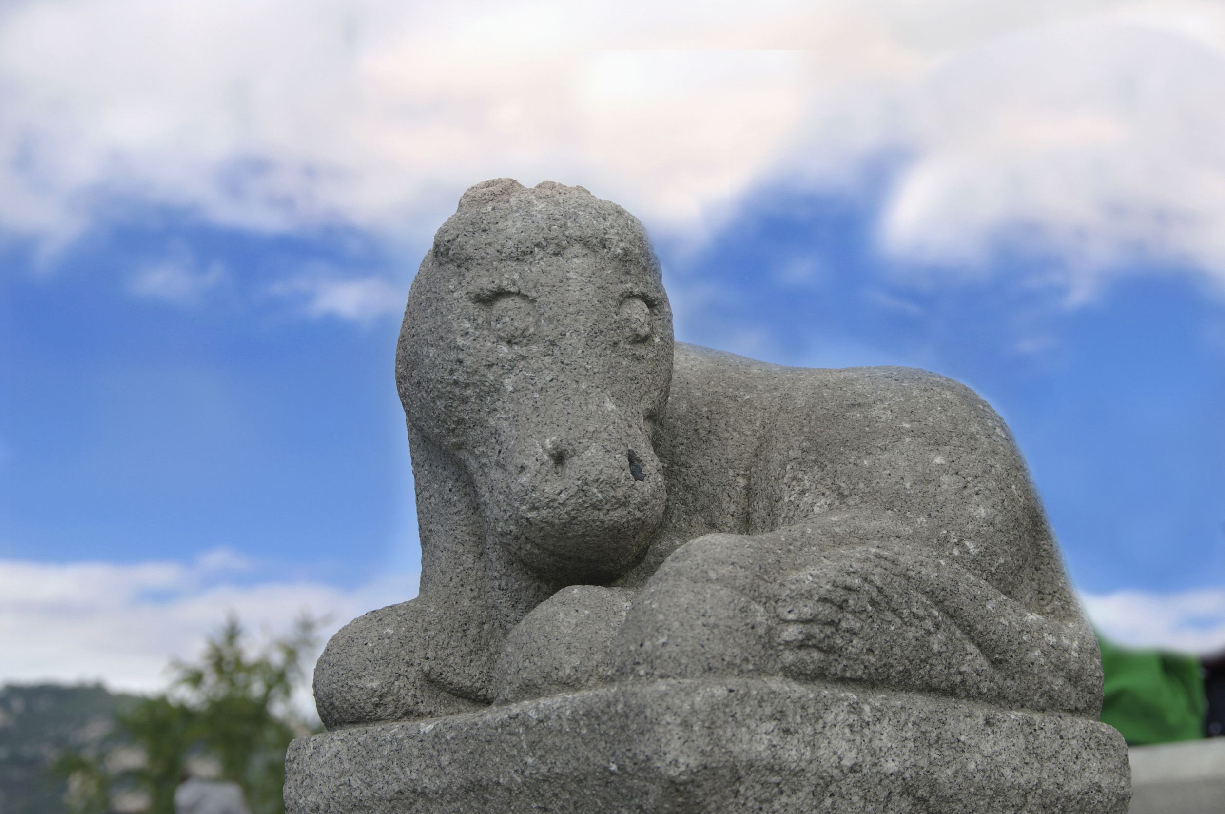 Steinskulptur eines ruhenden Pferdes vor blauem Himmelshintergrund