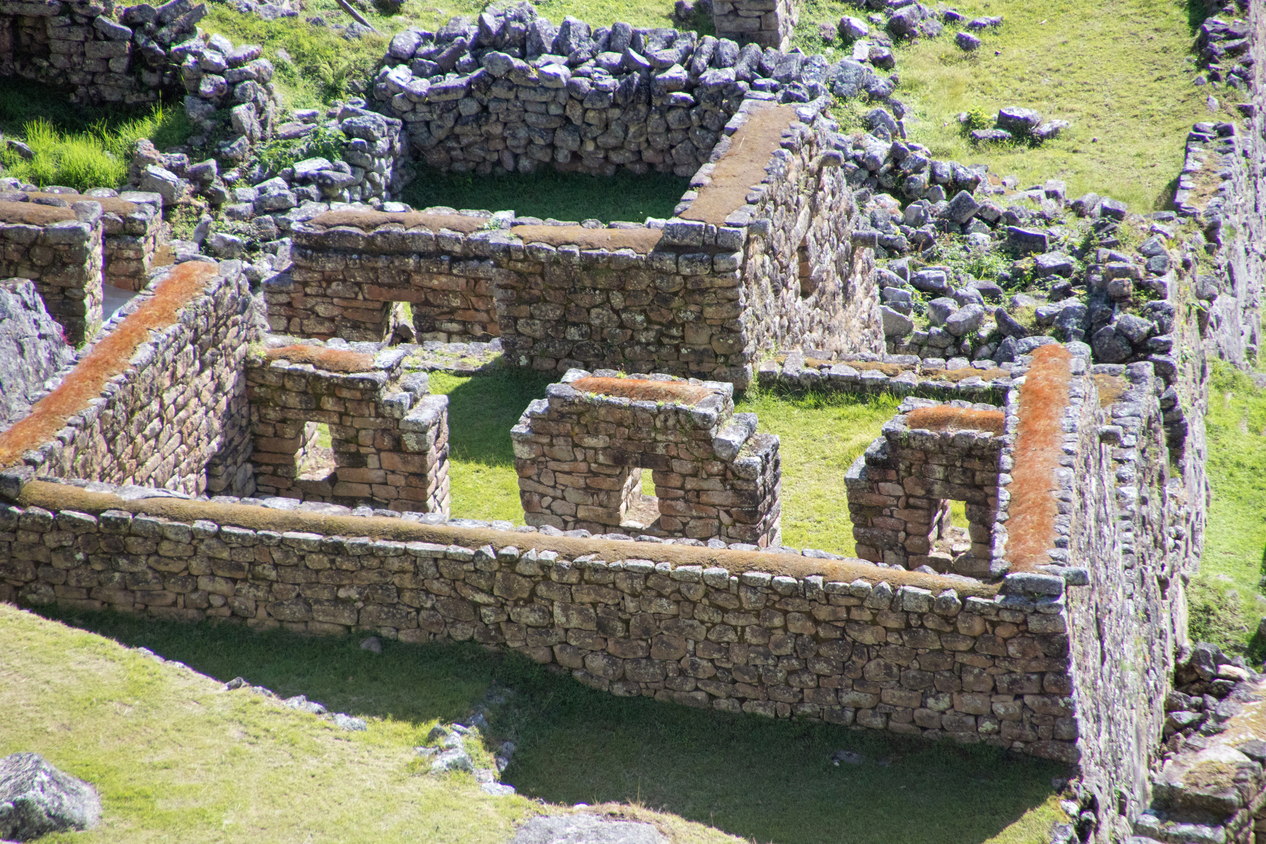 Ancient stone ruins with window openings, surrounded by green grass