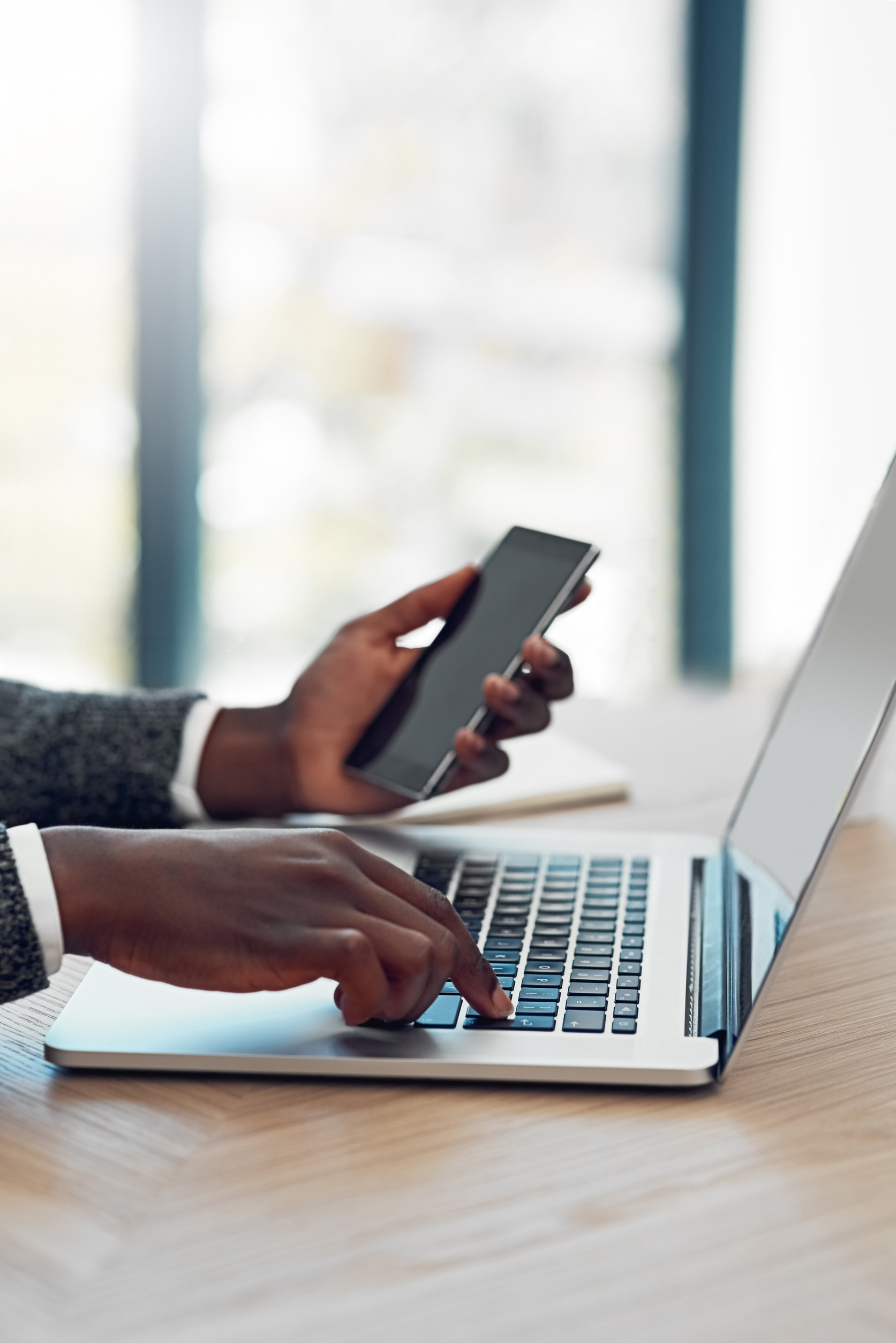 Man using a laptop while holding a phone