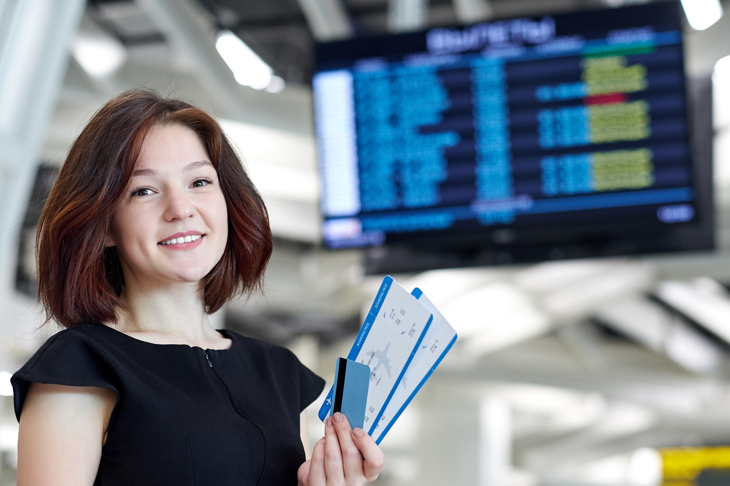 femme devant un panneau d'information à l'aéroport pour acheter un billet de vol, voyager en vacances