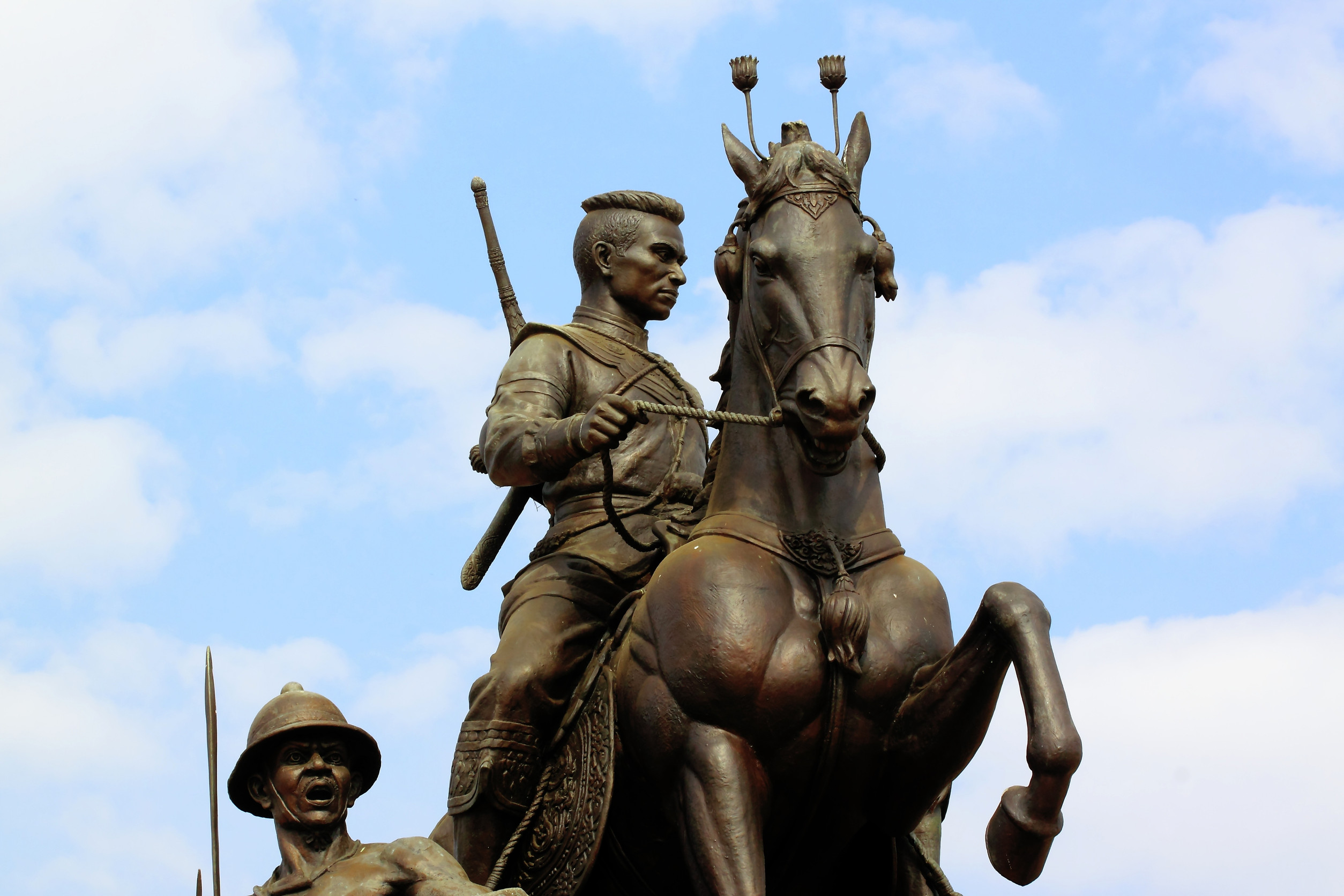 Reiterstandbild eines Kriegers mit Schwert, darunter ein Soldat, im Hintergrund der Himmel