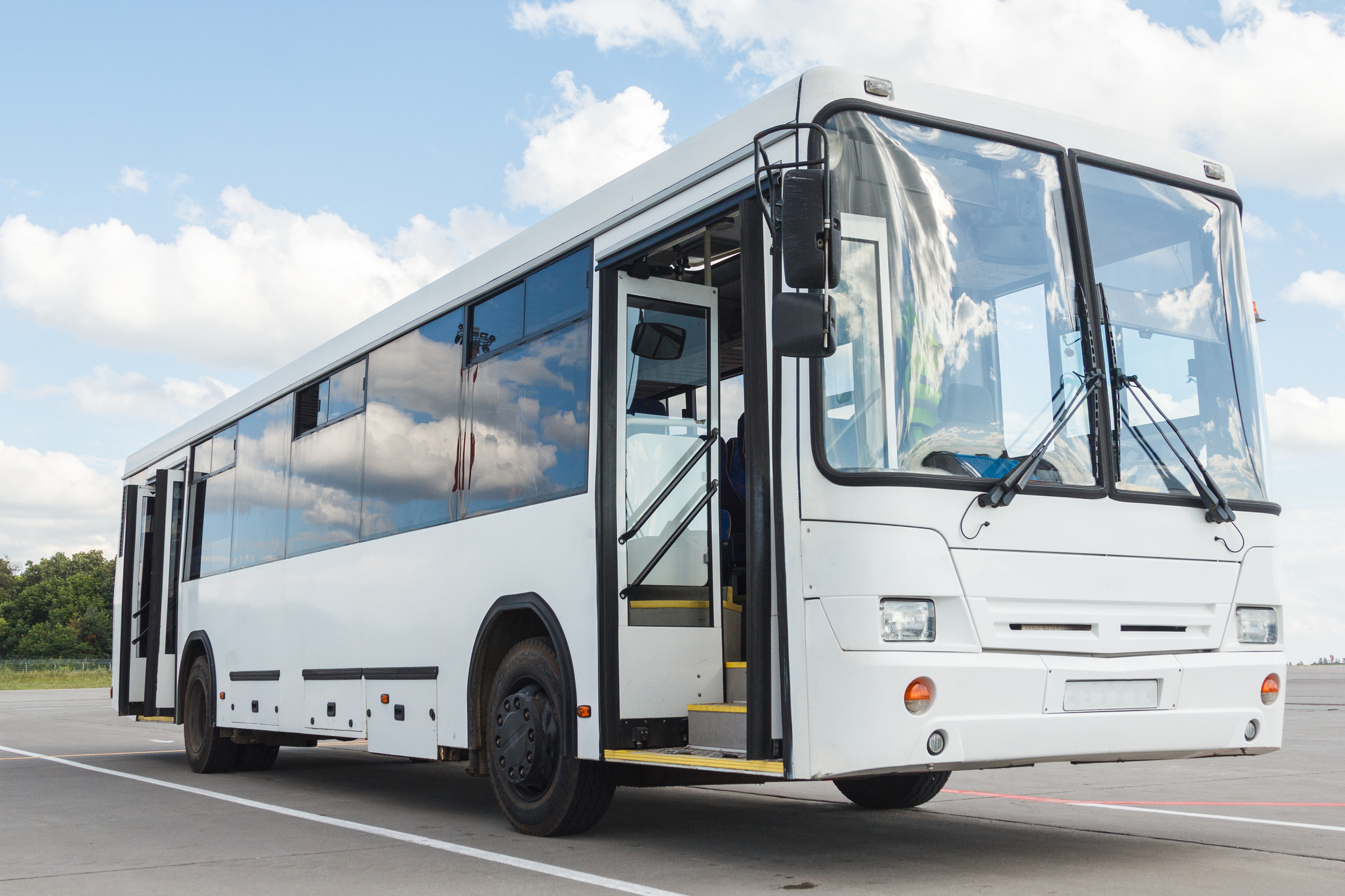 White public transport bus parked with open door on pavement