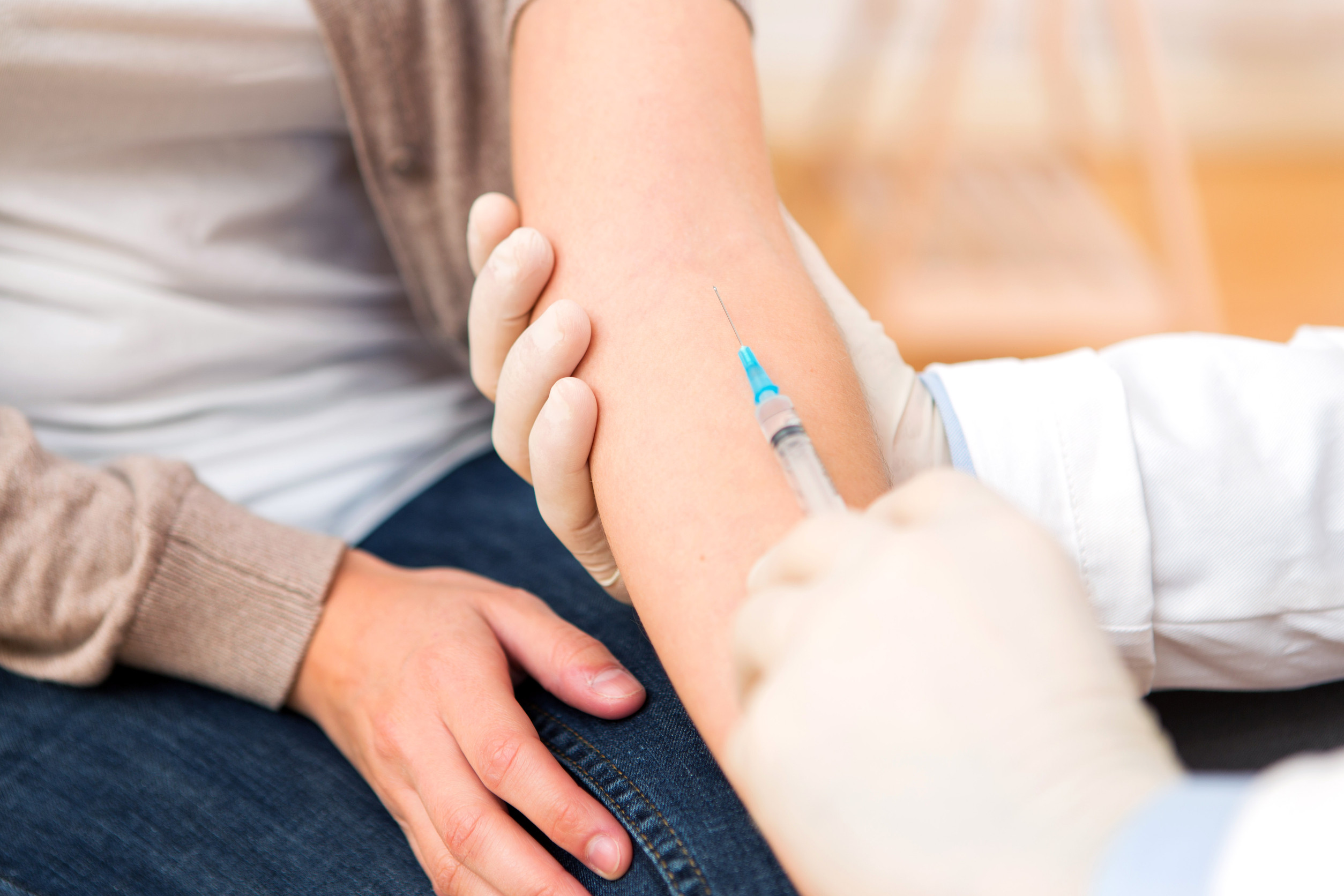 A healthcare professional administers an injection to a seated patient’s arm, ensuring hygiene with gloves.