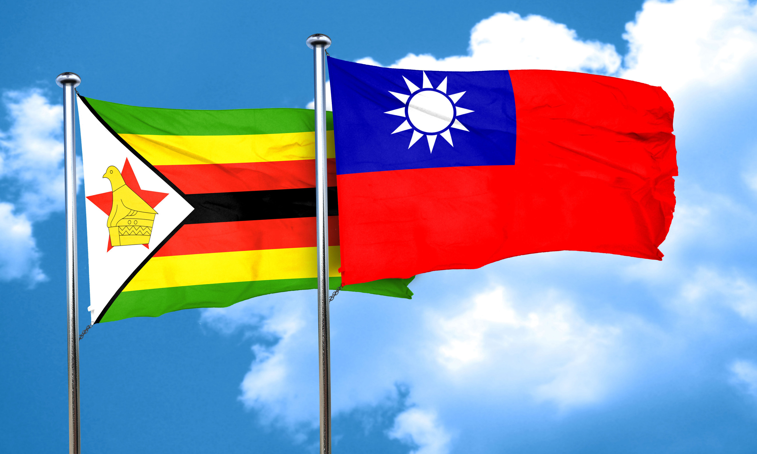 Flags of Zimbabwe and Taiwan waving in front of a blue sky with clouds